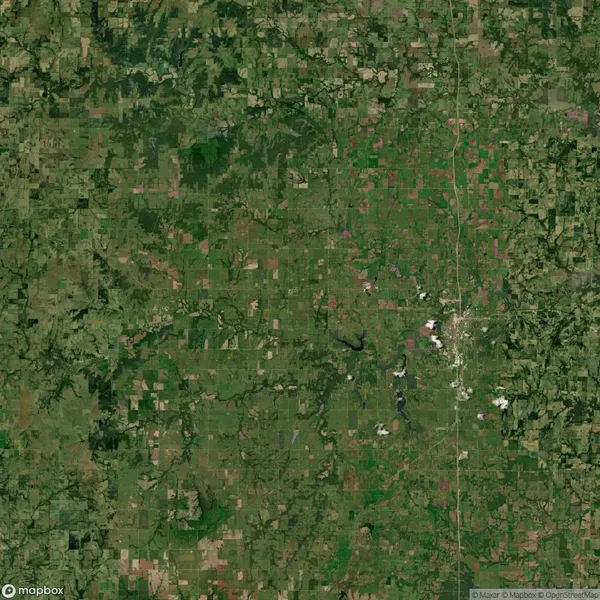 Aerial view of a rural landscape with patchwork fields, small forested areas, and scattered towns separated by roads.