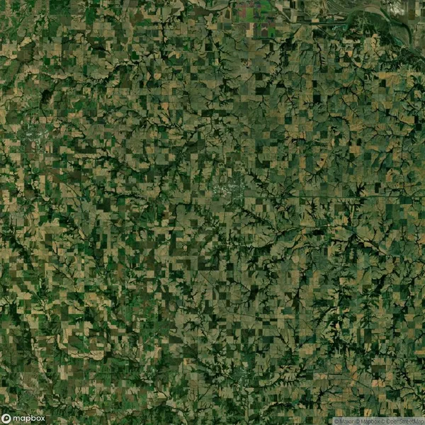 Aerial view of a rural landscape with a patchwork of agricultural fields, roads, and scattered wooded areas.