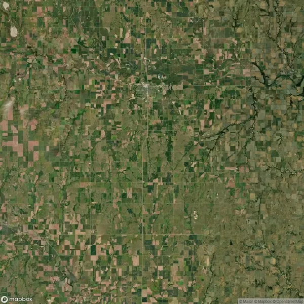 Aerial satellite view of a rural landscape with a patchwork of agricultural fields, roads, and scattered wooded areas.