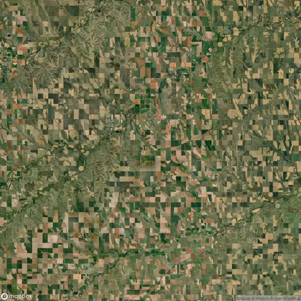 Aerial view of a patchwork of rectangular agricultural fields and green spaces, showing varied shades of brown and green in a rural landscape.