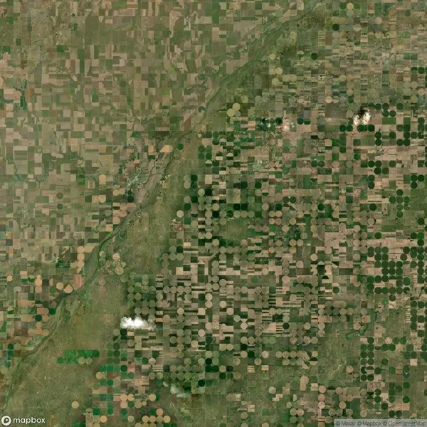Aerial view of farmland with a mix of square and circular crop fields, intersected by a river and scattered with a few small clouds.