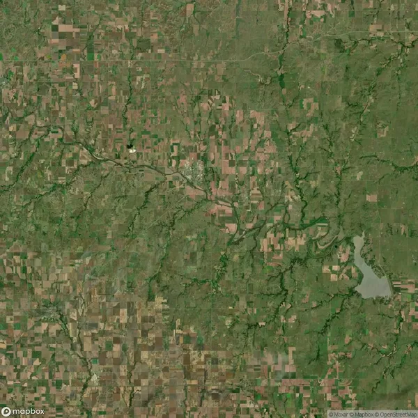 Aerial satellite view of a rural landscape with patchwork farmland, winding rivers, small town center, and a large lake in the lower right corner.