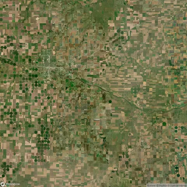 Aerial view of a patchwork landscape with rectangular and circular agricultural fields in shades of green and brown.