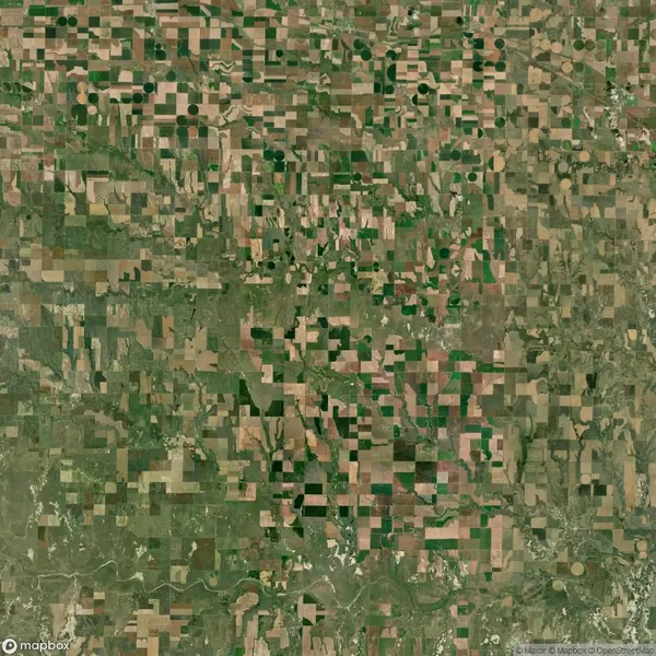 Aerial view of farmland with a patchwork pattern of rectangular and circular fields in various shades of green and brown.