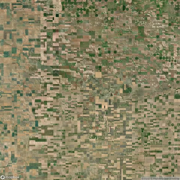 Aerial view of a patchwork landscape featuring rectangular and circular agricultural fields in various shades of green and brown.