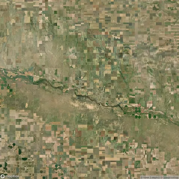 Aerial view of a patchwork landscape with rectangular agricultural fields, a winding river cutting across the center, and sparse vegetation.