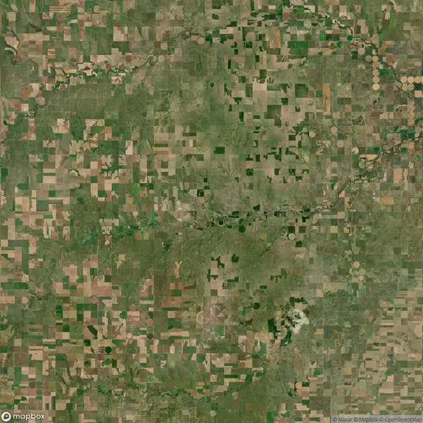 Aerial view of a large patchwork of agricultural fields and farmland, showing a mix of green and brown rectangular plots.