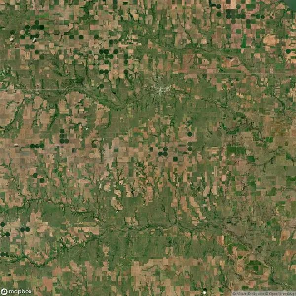 Aerial view of agricultural land showing a patchwork of rectangular fields and circular irrigated plots, interspersed with green areas and waterways.