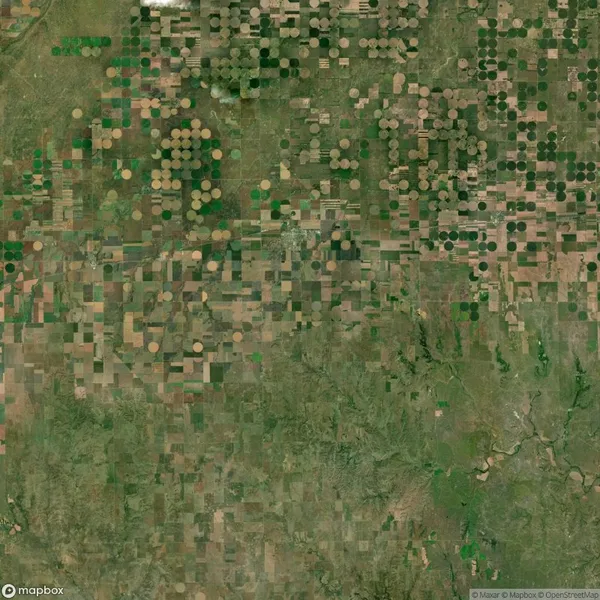 Aerial view of farmland with a mix of circular and rectangular crop fields in varying shades of green and brown.