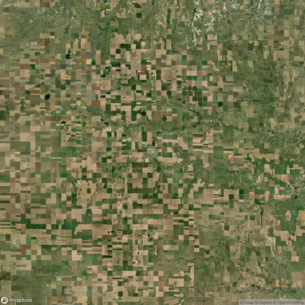 Aerial view of a rural landscape with a patchwork of rectangular and circular agricultural fields in various shades of green and brown.