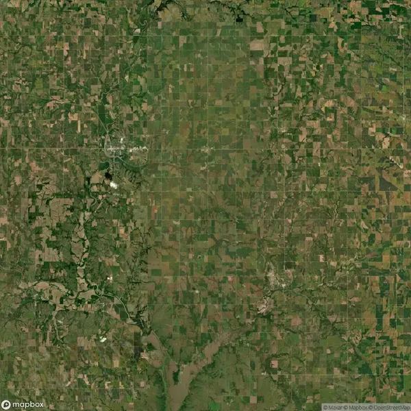 Aerial view of a patchwork of agricultural fields, roads, and scattered small towns, with a river and some wooded areas visible in the lower part of the image.