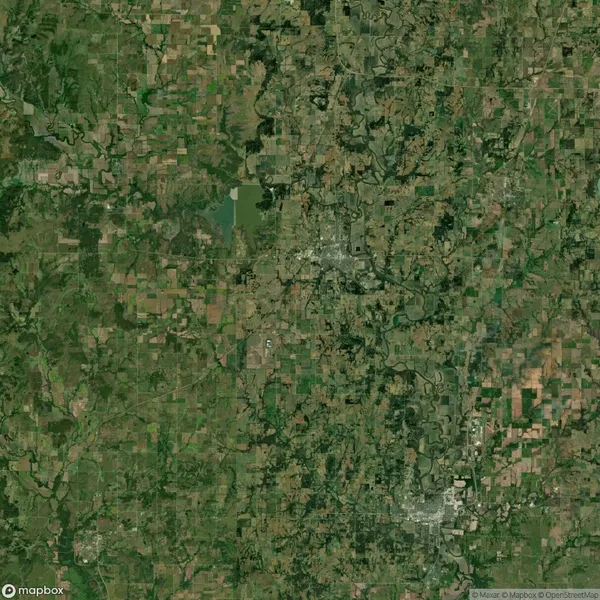 Satellite view of a rural landscape with fields, patches of forest, and two small towns visible near the center and lower right.