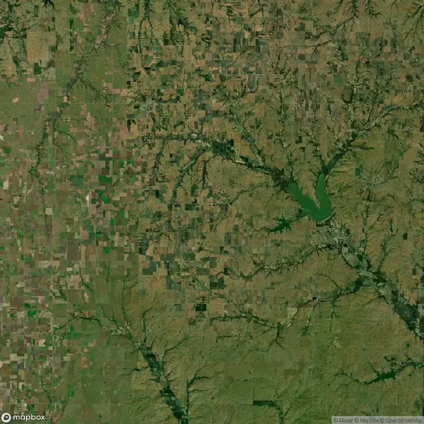 Satellite image showing a patchwork of agricultural fields, rivers, and a lake surrounded by varied terrain in a rural landscape.