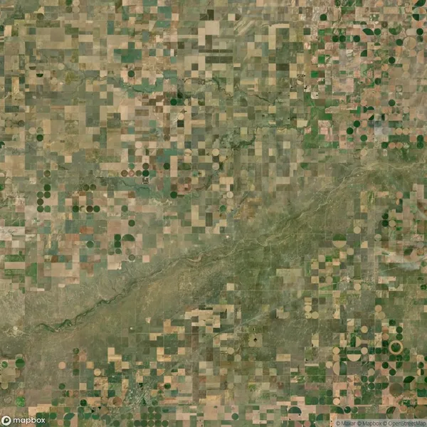 Aerial view of farmland with a patchwork pattern of rectangular and circular fields, divided by a winding river.