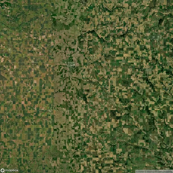 Aerial view of a rural landscape featuring a patchwork of agricultural fields, roads, and some forested areas.