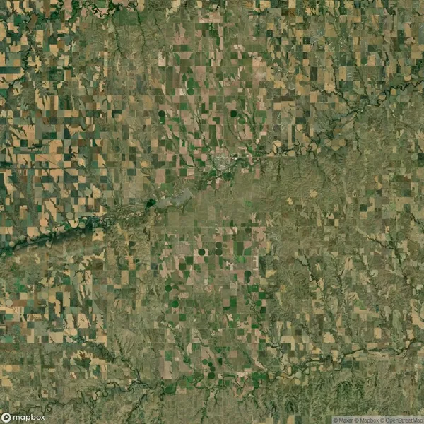 Aerial view of a rural landscape with a patchwork of agricultural fields, roads, and a meandering river running diagonally across the image.
