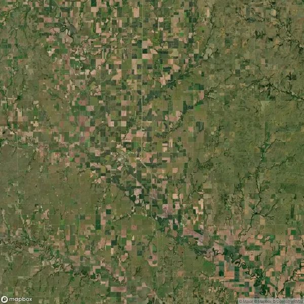 Aerial view of a rural landscape with a patchwork of agricultural fields, roads, and scattered wooded areas.