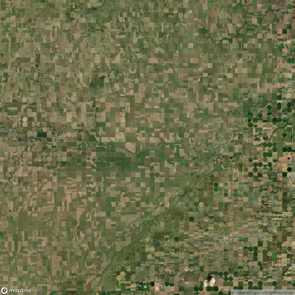 Aerial view of a rural landscape with a patchwork of rectangular and circular agricultural fields in varying shades of green and brown.