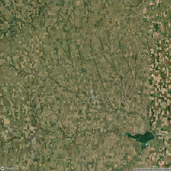 Satellite view of a rural landscape featuring patchwork farmland, some wooded areas, a reservoir in the lower right, and a network of roads and rivers.