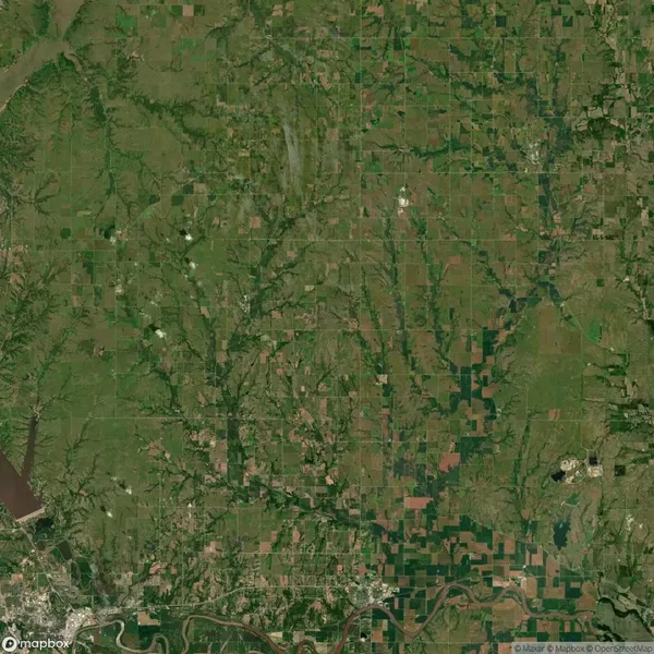 Aerial view of a rural landscape with patchwork fields, winding rivers, and scattered wooded areas. A city and river are visible in the lower part of the image.