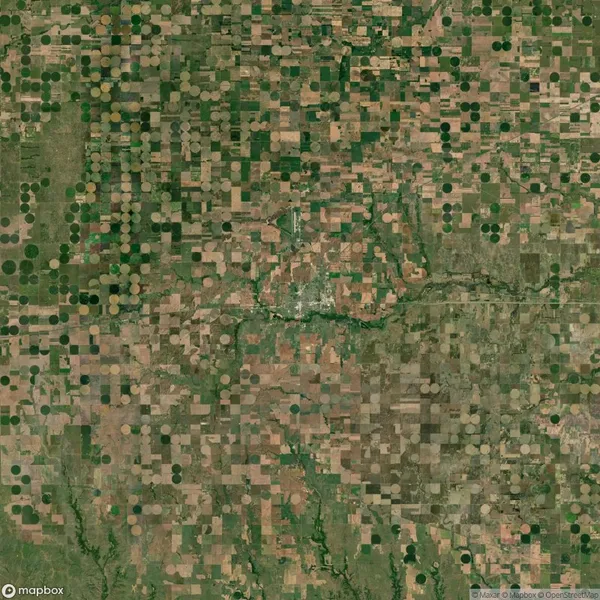 Aerial view of farmland with a patchwork of square and circular crop fields, intersected by a river running through the center.
