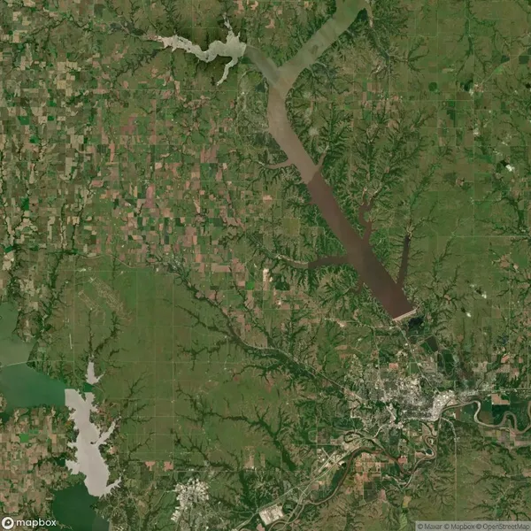 Satellite image showing a large reservoir, farmland, and a city with a river system; the terrain is mostly green and patchworked with agricultural fields.
