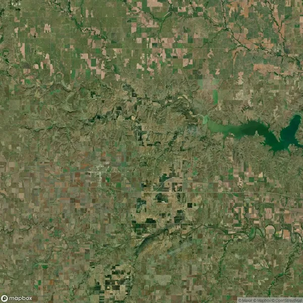 Aerial satellite view of a rural landscape with patchwork fields, winding rivers, and a large lake in the upper right corner.