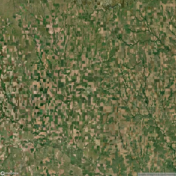 Aerial view of a rural landscape with a patchwork pattern of green and brown agricultural fields separated by roads and natural vegetation.