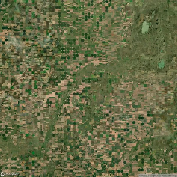 Aerial view of farmland with a grid of square and circular crop fields in varying shades of green and brown.
