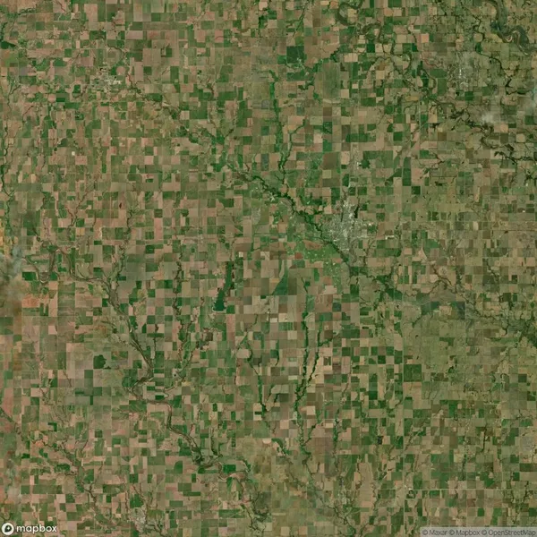 Aerial view of a patchwork landscape of rectangular agricultural fields with scattered green areas and a few winding rivers or streams.