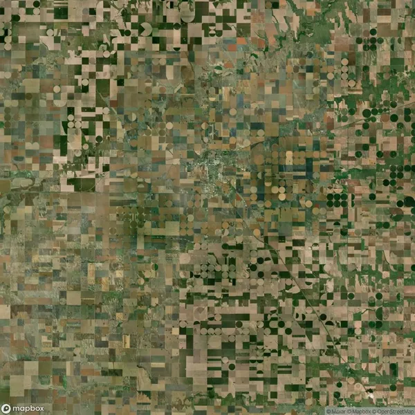 Aerial view of agricultural land showing a patchwork of square and circular crop fields in various shades of green and brown.