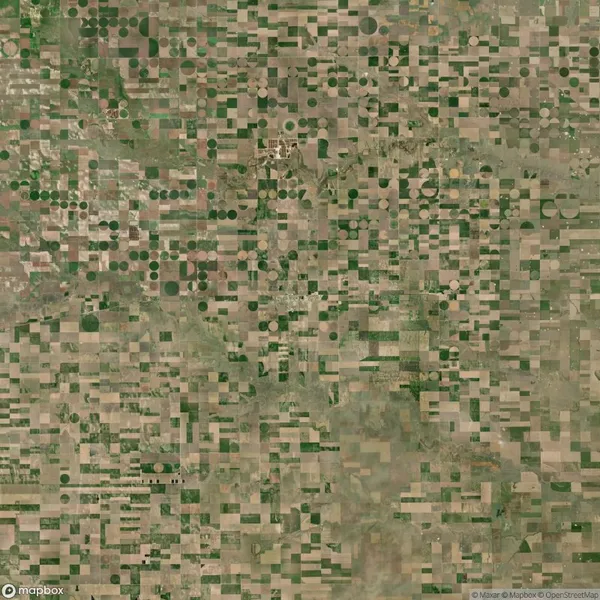 Aerial view of farmland with a grid pattern of square and circular crop fields in various shades of green and brown.