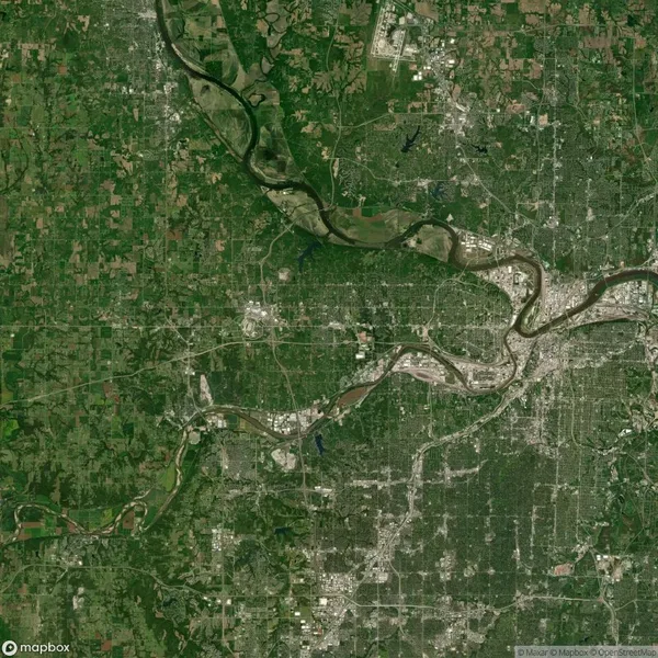 Satellite image showing a city with a river flowing through it, surrounded by green areas and a network of roads and buildings.