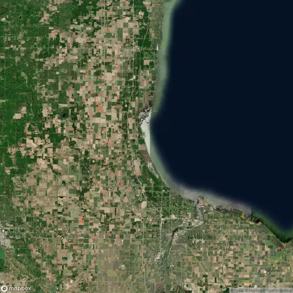Satellite view of a region with a grid of farmland, a large body of water on the right, and urban areas near the shoreline.