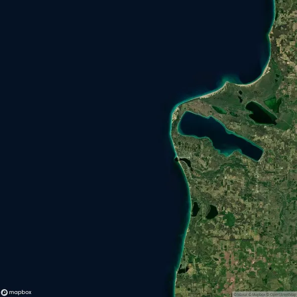 Satellite view of a coastal area showing a curved shoreline, inland lakes, agricultural fields, and green vegetation bordering a large body of water.
