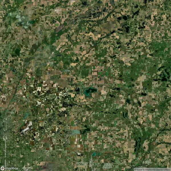 Aerial satellite image showing a patchwork of farmland, fields, scattered lakes, and small towns in a rural area.