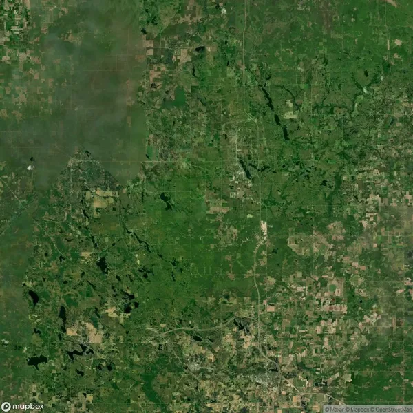 Aerial satellite view of a green, rural landscape with scattered patches of farmland, roads, and small wooded areas.