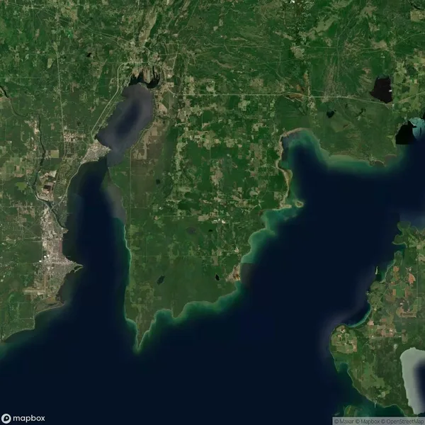 Satellite view of a green, forested peninsula bordered by water on three sides, with some urban areas and roads visible in the surrounding landscape.