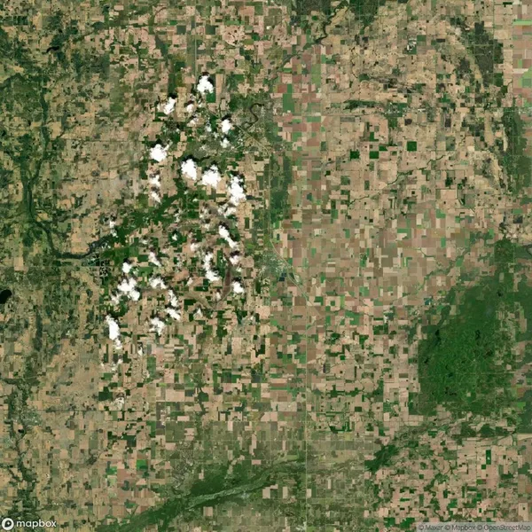 A satellite view shows a patchwork of agricultural fields, scattered clouds, and some areas of dense greenery and forest.
