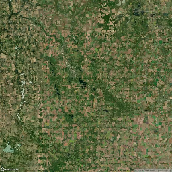 Aerial view of a patchwork landscape with farmland, fields, and scattered green areas in a rural region.