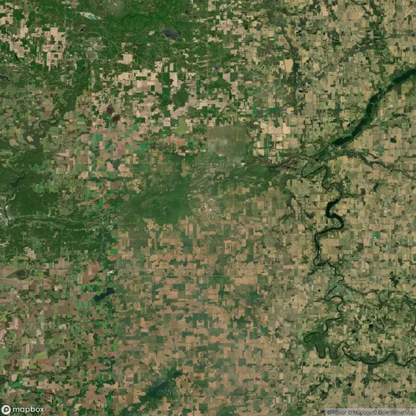A satellite view of a patchwork landscape with agricultural fields, green areas, and a winding river on the right side.