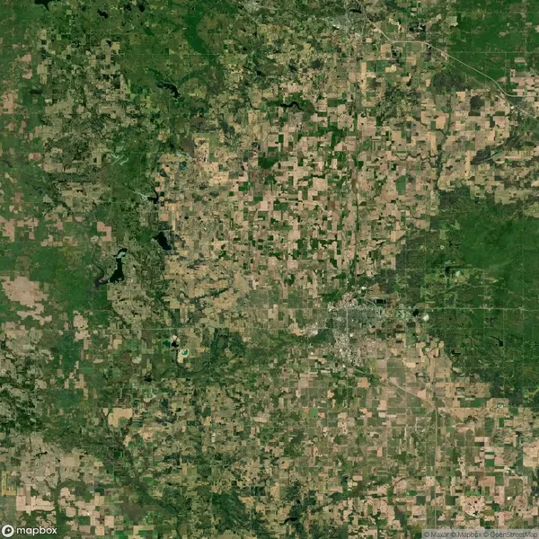 A satellite view showing a patchwork of agricultural fields, roads, and scattered wooded areas in a rural landscape.