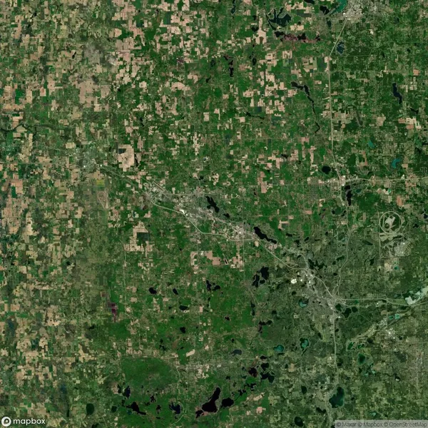 A satellite view showing a patchwork of farmland, scattered lakes, and urban areas with road networks in a predominantly green landscape.