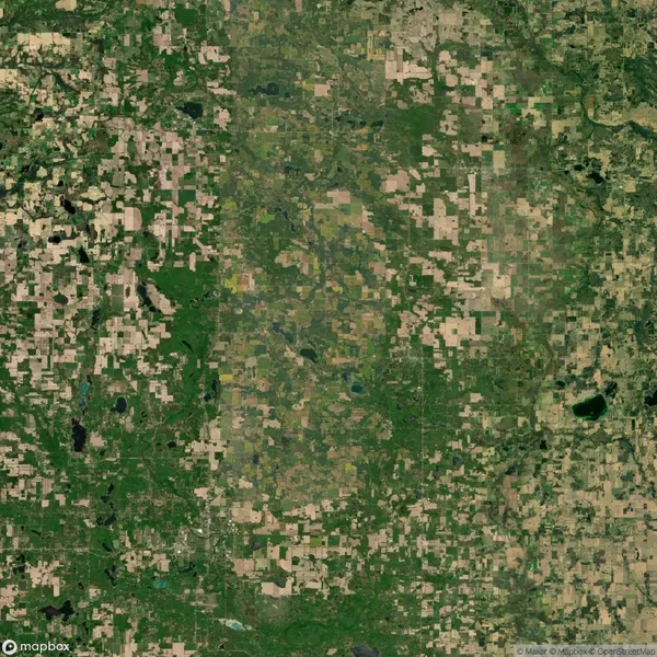 Aerial satellite view of a rural landscape with a patchwork of green and tan agricultural fields, roads, and scattered bodies of water.