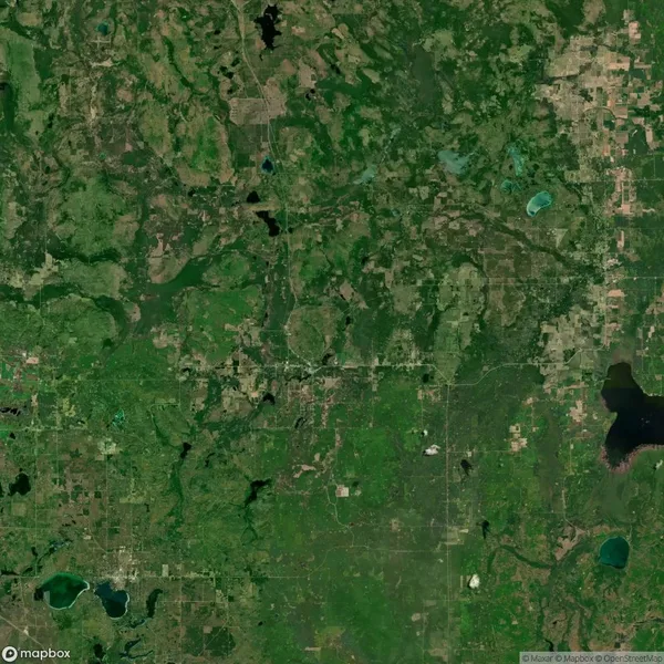 Aerial satellite view of a predominantly green, rural landscape with scattered lakes, patches of forest, and agricultural fields.