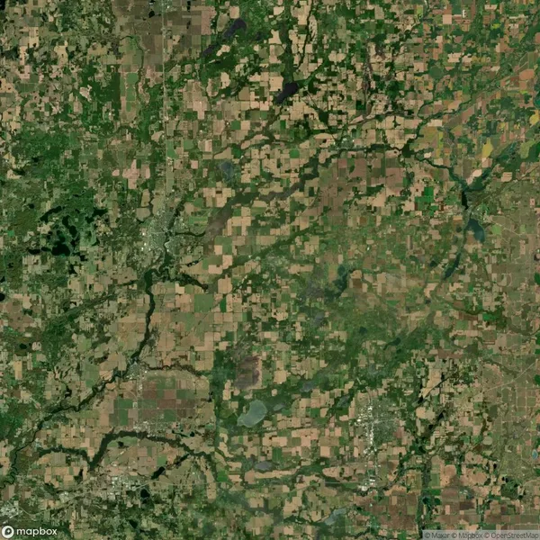 Aerial satellite view of a rural landscape with a patchwork of agricultural fields, forests, rivers, and scattered small settlements.