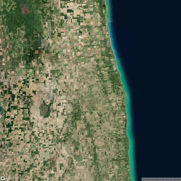 Satellite view of a patchwork of agricultural fields and rural land next to a long stretch of coastline with blue and green water.