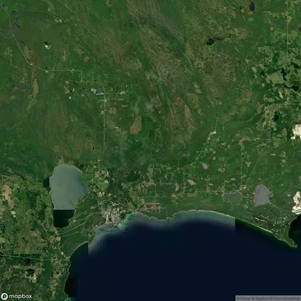 Satellite image showing a coastal area with a bay, several lakes, and green land dotted with roads and farmland.