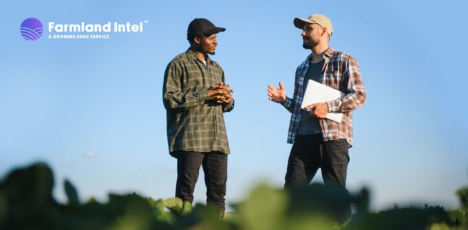 Two men in casual clothing stand in a field having a conversation; one holds a laptop. "Farmland Intel" logo appears in the top left corner.